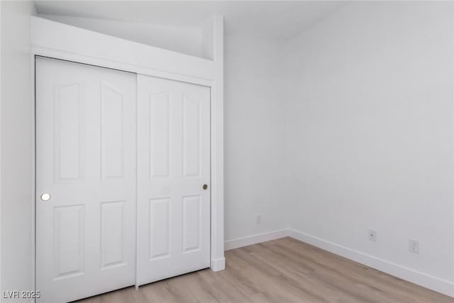 unfurnished bedroom with light wood finished floors, baseboards, and a closet