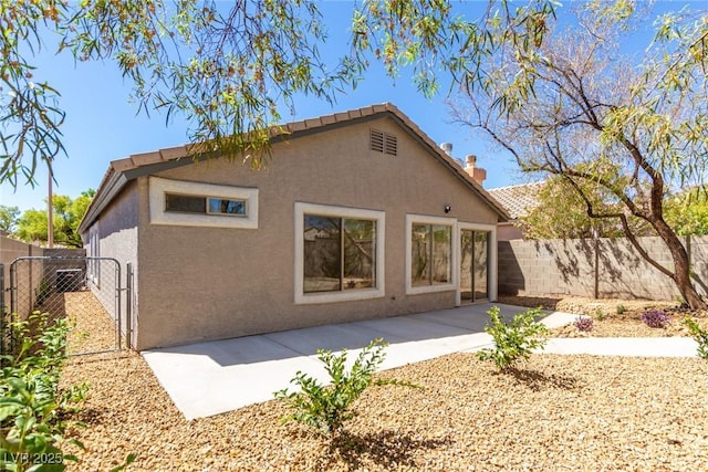 back of house with stucco siding, fence, a chimney, and a patio