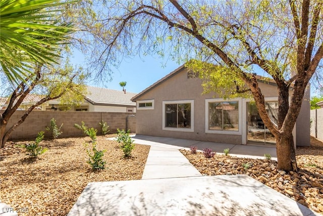 rear view of property featuring stucco siding, a fenced backyard, and a patio area