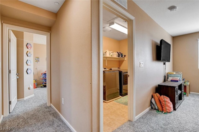hall featuring separate washer and dryer, carpet floors, and baseboards