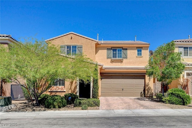 view of front facade featuring a garage, decorative driveway, and stucco siding