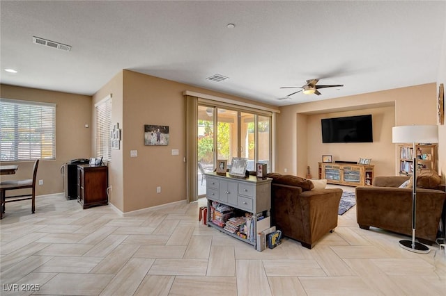 living room with healthy amount of natural light, ceiling fan, and baseboards