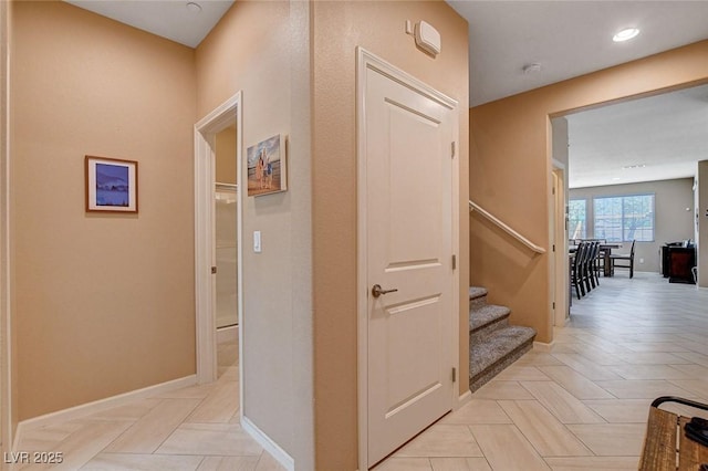 hallway featuring baseboards, stairs, and recessed lighting