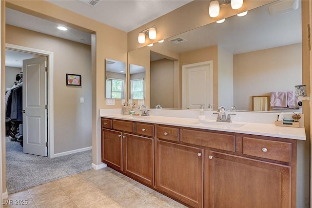 bathroom featuring baseboards, double vanity, and a walk in closet