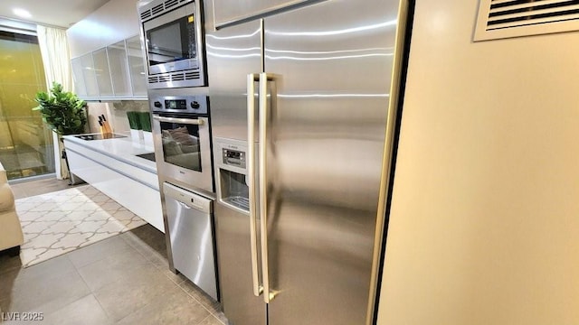 kitchen featuring appliances with stainless steel finishes, white cabinetry, light tile patterned floors, and light countertops