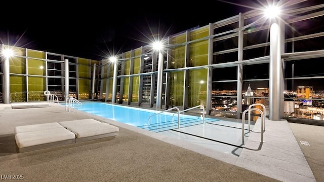 pool at night with a community pool and a patio area