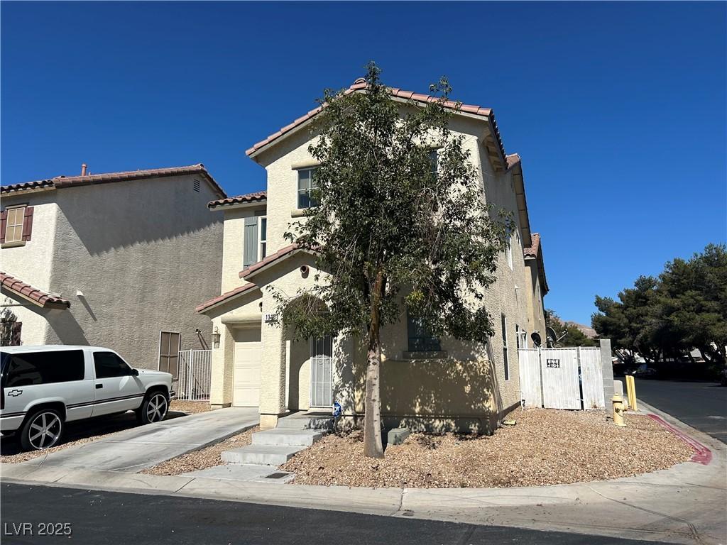 1310 Golden Apple St, Las Vegas, NV 89142 - view of front of property with stucco siding, a garage, a tiled roof, and driveway