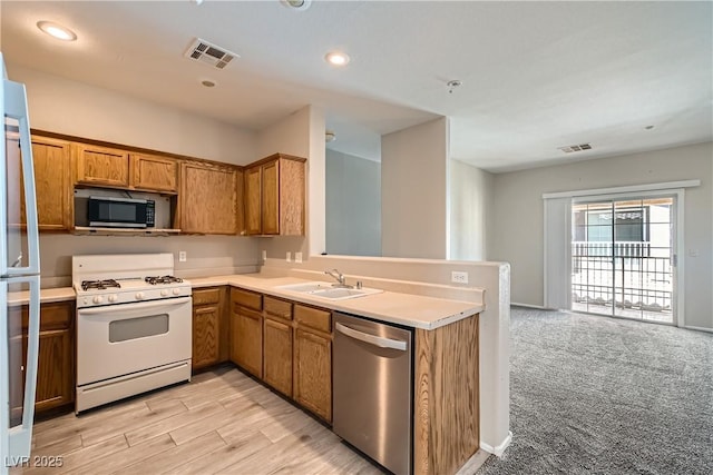 5915 Nuevo Leon St Unit 8, North Las Vegas, NV 89031 - kitchen with appliances with stainless steel finishes, brown cabinets, light countertops, a peninsula, and recessed lighting