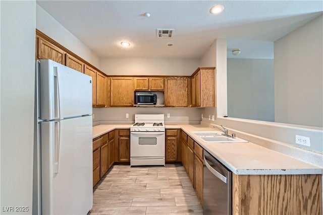 5915 Nuevo Leon St Unit 8, North Las Vegas, NV 89031 - kitchen with white appliances, brown cabinets, light countertops, light wood-style floors, and recessed lighting