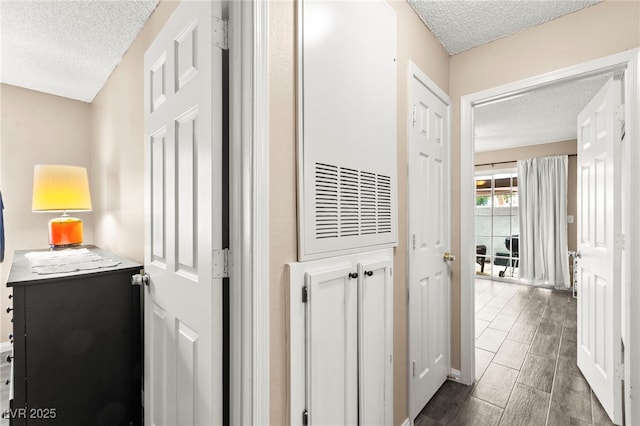 corridor featuring a textured ceiling and baseboards