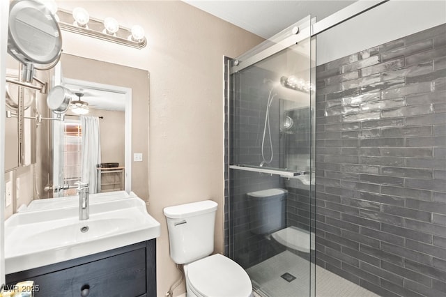 bathroom with a stall shower, toilet, vanity, and ceiling fan