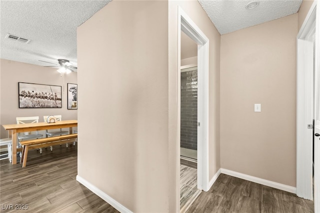 hall with a textured ceiling, wood finished floors, and baseboards
