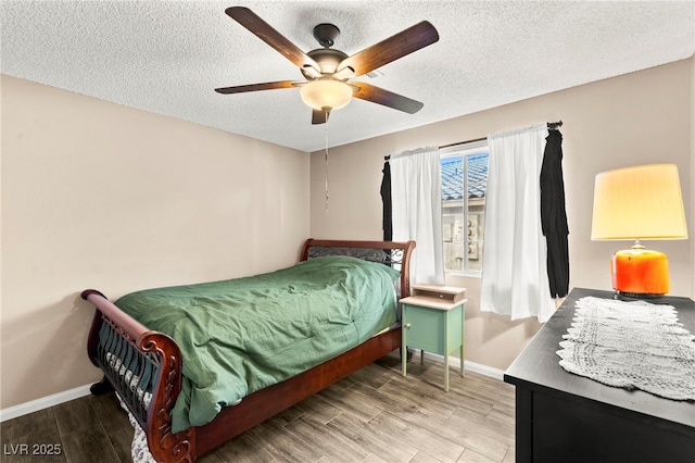bedroom featuring baseboards, wood finished floors, a textured ceiling, and a ceiling fan