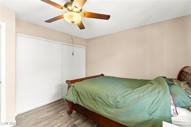 bedroom featuring wood finished floors, a closet, a ceiling fan, and a textured ceiling