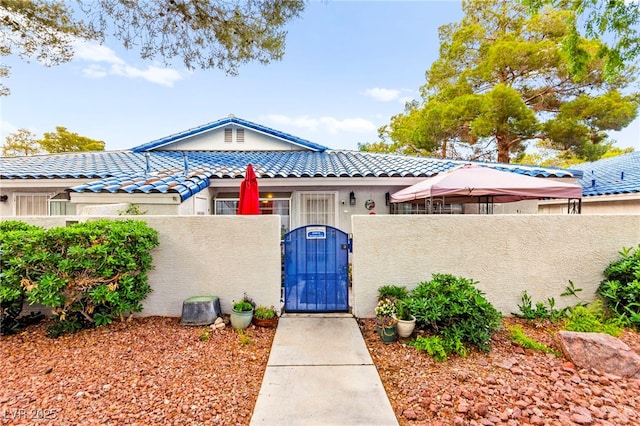 view of front of property with a fenced front yard, a gate, a tiled roof, and stucco siding