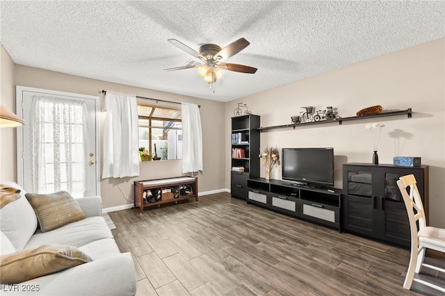 living room with a ceiling fan, wood finished floors, baseboards, and a textured ceiling