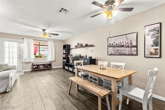 dining space featuring a ceiling fan, a textured ceiling, wood finished floors, and baseboards