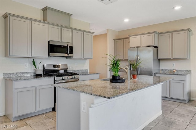kitchen with stainless steel appliances, a sink, light stone countertops, gray cabinetry, and recessed lighting