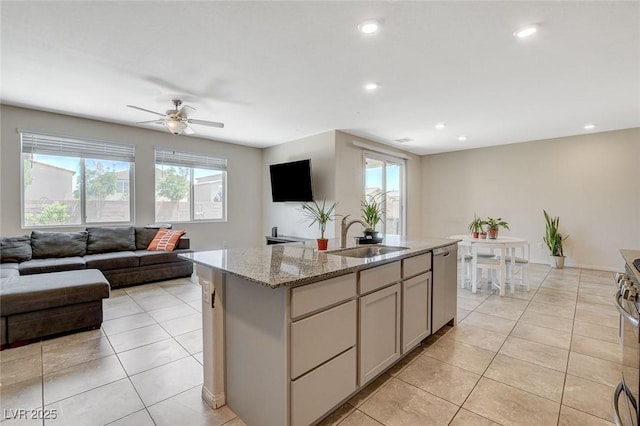 kitchen featuring a sink, appliances with stainless steel finishes, open floor plan, light tile patterned floors, and light stone countertops