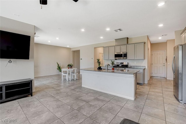 kitchen featuring appliances with stainless steel finishes, gray cabinets, light tile patterned flooring, a center island with sink, and recessed lighting