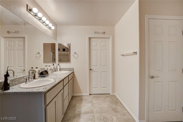 bathroom featuring baseboards, double vanity, and tile patterned floors