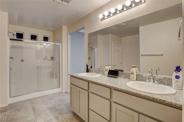 full bathroom featuring a shower stall, double vanity, tile patterned flooring, and baseboards