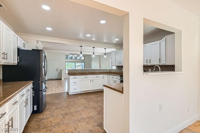 4302 Newhaven Dr, Las Vegas, NV 89147 - kitchen with a peninsula, dark countertops, decorative backsplash, freestanding refrigerator, and crown molding