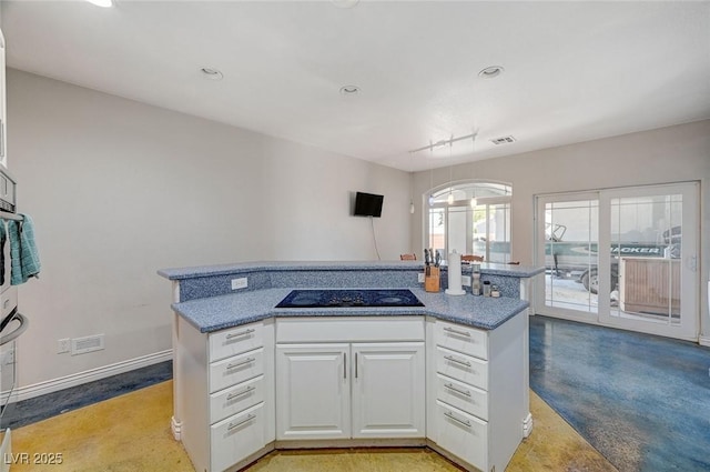1420 Logandale Dr, Logandale, NV 89021 - kitchen with black electric stovetop, white cabinets, concrete flooring, recessed lighting, and baseboards