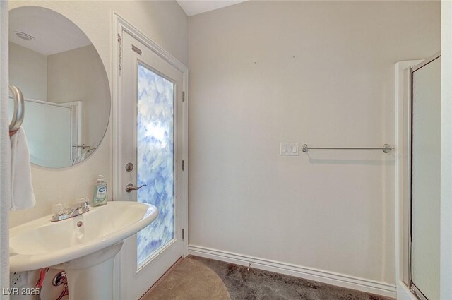 1420 Logandale Dr, Logandale, NV 89021 - bathroom featuring healthy amount of natural light, a shower with door, baseboards, and a sink