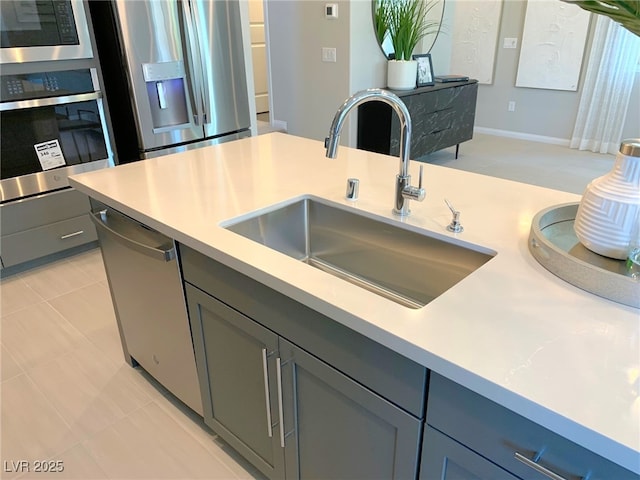 6511 Dove Point Pl, Las Vegas, NV 89130 - kitchen with stainless steel appliances, a sink, light countertops, and gray cabinetry