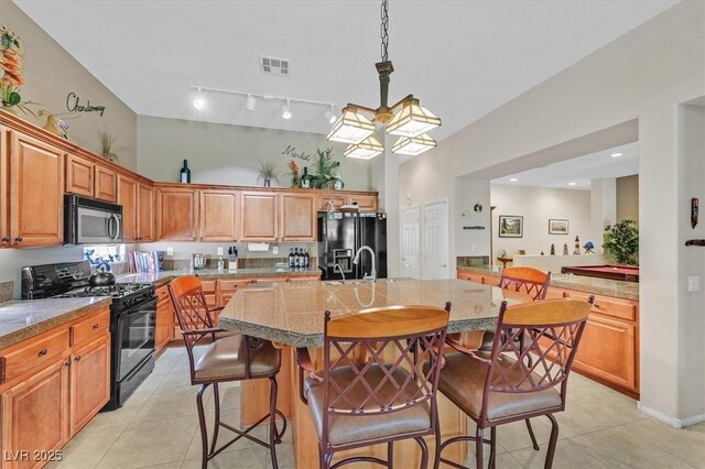 8208 Flowing Rapids Ct, Las Vegas, NV 89131 - kitchen with black appliances, light tile patterned floors, a kitchen breakfast bar, an island with sink, and light countertops