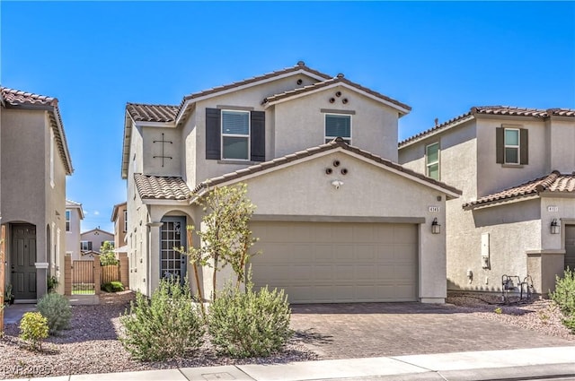mediterranean / spanish-style home featuring stucco siding, a garage, decorative driveway, and a tiled roof