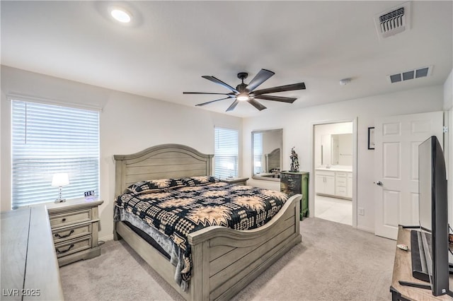 bedroom featuring light colored carpet, connected bathroom, ceiling fan, and baseboards