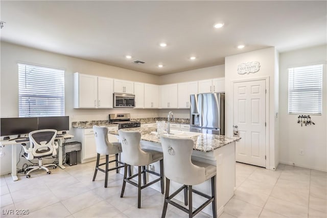 kitchen featuring stainless steel appliances, a kitchen island with sink, a breakfast bar area, recessed lighting, and a sink