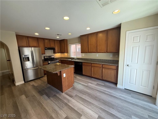 kitchen with stainless steel appliances, a sink, a kitchen island, recessed lighting, and dark wood-style flooring
