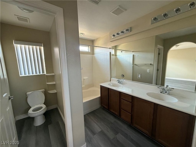 full bath with wood finished floors, double vanity, toilet, and shower / bathtub combination