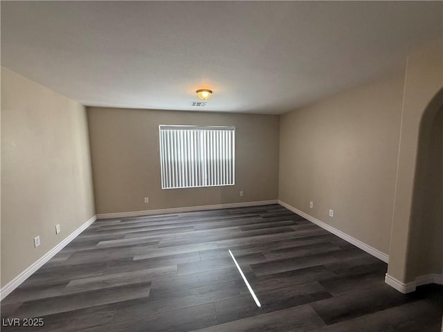 spare room featuring dark wood-style flooring and baseboards