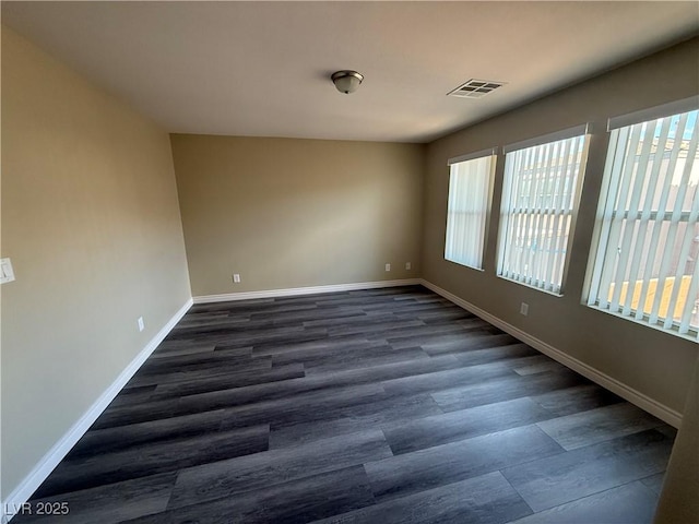 spare room with healthy amount of natural light, dark wood finished floors, and baseboards