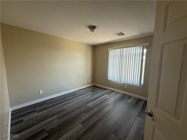 spare room with dark wood-style flooring and baseboards