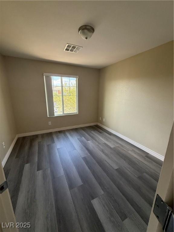 spare room with dark wood-style flooring and baseboards