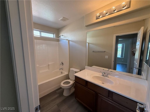 bathroom with wood finished floors, toilet, a textured ceiling, vanity, and  shower combination