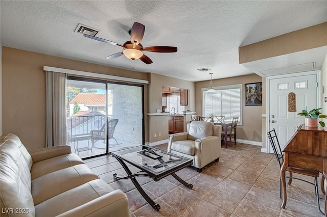 living room with plenty of natural light, ceiling fan, baseboards, and a textured ceiling