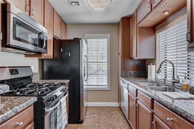 kitchen with stainless steel appliances, a sink, baseboards, and plenty of natural light