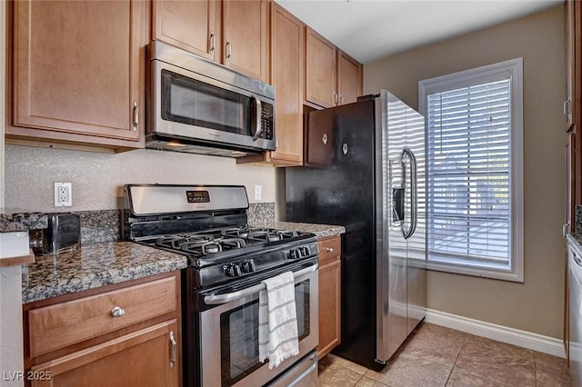 kitchen with stainless steel appliances, baseboards, and light tile patterned floors