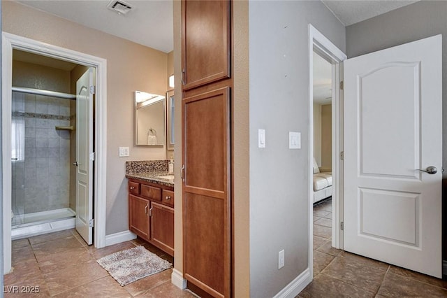 bathroom featuring tile patterned floors, vanity, a stall shower, and baseboards