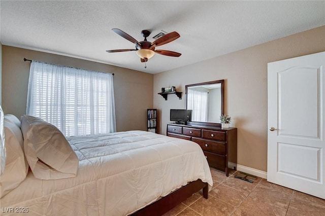 bedroom featuring multiple windows, tile patterned floors, baseboards, ceiling fan, and a textured ceiling