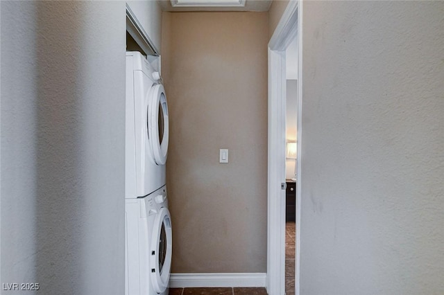 washroom with stacked washer / dryer, tile patterned floors, and baseboards