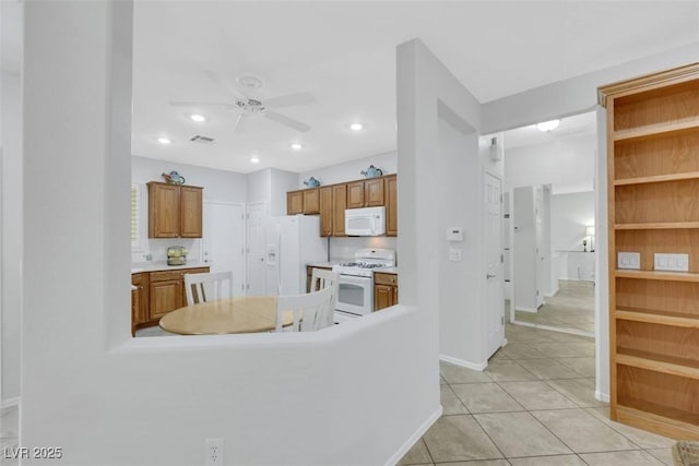 kitchen featuring white appliances, a ceiling fan, baseboards, brown cabinets, and light countertops