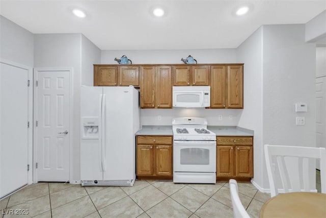 kitchen featuring white appliances, light countertops, brown cabinetry, light tile patterned floors, and recessed lighting
