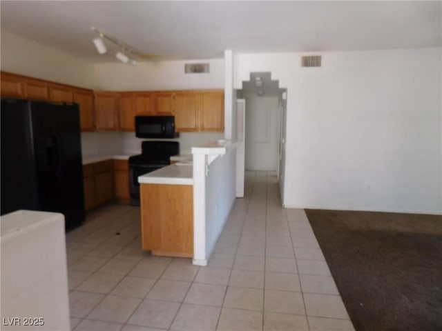 kitchen featuring black appliances, light tile patterned floors, light countertops, and a peninsula